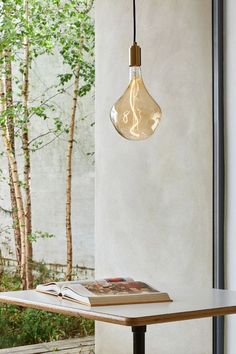 a table with a book on it and a light bulb hanging from the ceiling