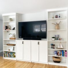 a living room with white bookcases and a flat screen tv mounted on the wall