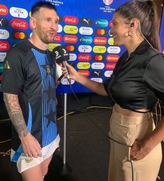 a man and woman talking to each other while standing in front of a tv screen