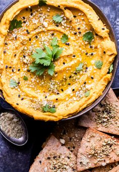 hummus and pita chips on a plate with some garnishes around it