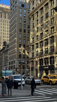 people are crossing the street in front of tall buildings