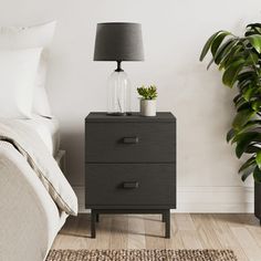 a bedroom scene with focus on the bedside table and plant next to it's bed