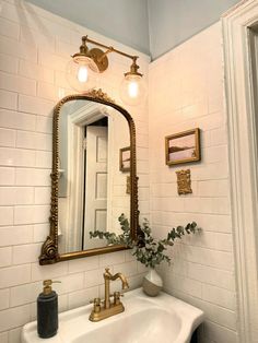 a bathroom sink sitting under a mirror next to a light on top of a wall