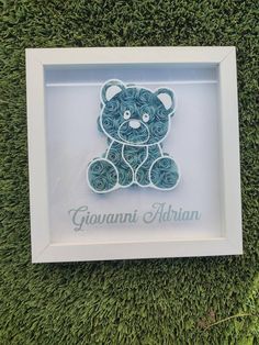 a blue teddy bear in a white shadow box