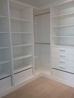 an empty closet with white shelves and drawers