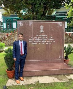 a man in a suit standing next to a monument with the words in memory on it