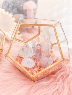 some rocks and crystals are in a glass container on a pink furnishing area