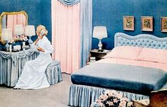 a woman sitting on a bed in a room with blue walls and pink drapes