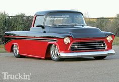 an old black and red truck parked on the street