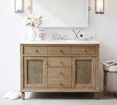 a bathroom vanity with a mirror above it and flowers in the vase on the counter