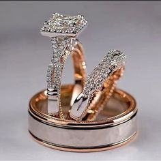 two wedding rings are sitting on top of each other in gold and silver with diamonds