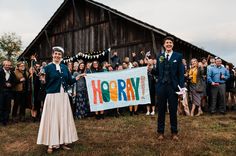 two people standing in front of a crowd holding a sign that says hooray