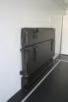 a black refrigerator sitting in the corner of a room next to a white wall and floor