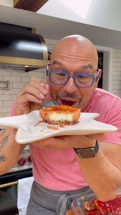 a man with glasses eating food from a white plate on top of a kitchen counter