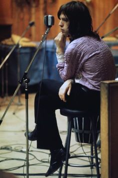 a woman sitting in front of a microphone on top of a chair next to a keyboard