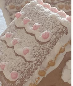 there is a large piece of cake with white frosting and pink decorations on it