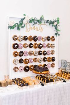 a table topped with lots of donuts on top of a white cloth covered table