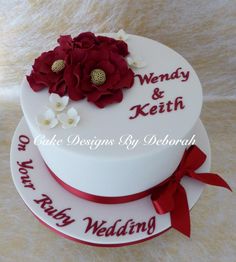 a wedding cake decorated with red flowers and white icing on a furnished surface