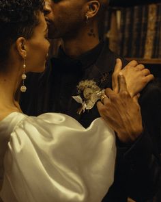 a man and woman kissing each other in front of bookshelves