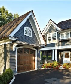 a large house with two garages on each side and flowers in the front yard