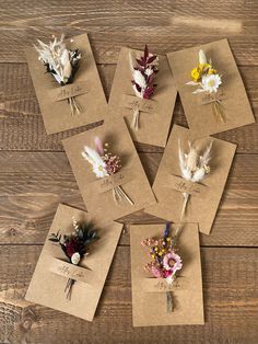 six different types of dried flowers on brown paper laid out on a wooden table top