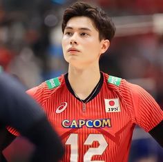 a young man wearing a red uniform standing in front of a crowd