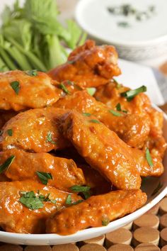 a white plate topped with chicken wings covered in sauce and garnished with parsley