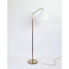 a floor lamp with a white shade on it's base and a gold plated metal base