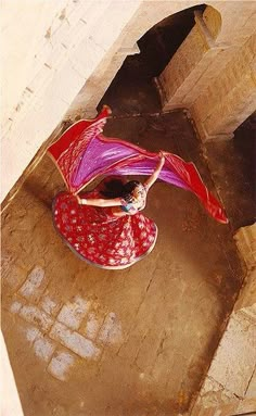 an aerial view of a woman in a red and white dress holding a pink umbrella