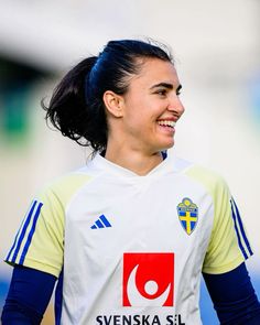 a female soccer player is smiling and looking to the side with her hair in a ponytail