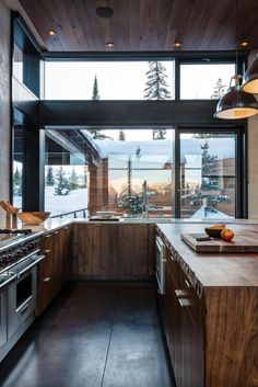 a kitchen with wooden cabinets and stainless steel appliances in the middle of snow covered mountains