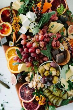 an assortment of fruits and vegetables on a cutting board with cheese, crackers, grapes, walnuts