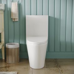 a white toilet sitting in a bathroom next to a trash can and towel dispenser