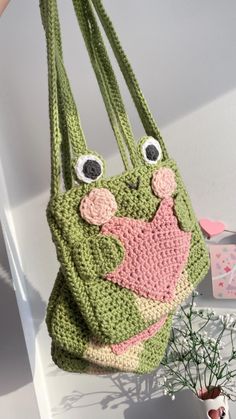 a crocheted purse hanging from a hook with eyes and nose on it's side