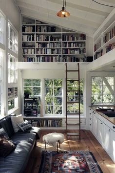 a living room filled with lots of furniture and bookshelves next to a window