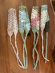 three crocheted headbands sitting on top of a wooden table next to an eyeglass case