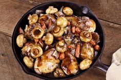 a skillet filled with meat and vegetables on top of a wooden table