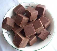 a white bowl filled with chocolate pieces on top of a green and white table cloth