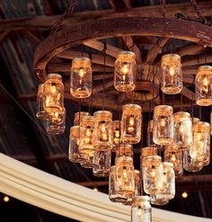 a chandelier made out of mason jars hanging from a ceiling in a barn