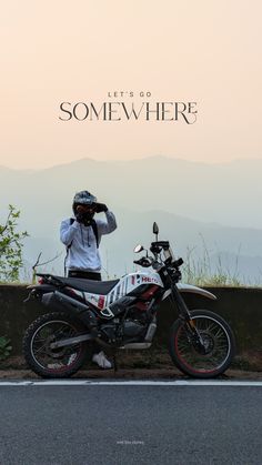 a man standing next to a motorcycle on the side of a road