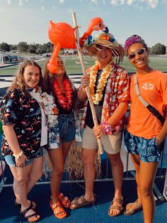 four girls are posing for the camera with orange floats on their heads and one girl is holding a stick