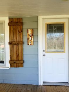 two wooden shutters on the side of a house with a white door and window