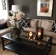 a living room with two couches and candles on the coffee table in front of it