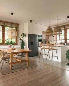 an open kitchen and dining room area with wood floors, white walls, and large windows