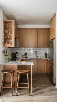 two stools are in the middle of a kitchen counter with wooden cabinets and white tile