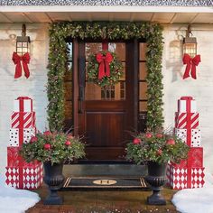 christmas decorations on the front door of a house with wreaths and bows around it