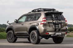 a silver four - doored suv parked on the road with its roof rack extended