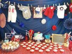 a table topped with cupcakes and cakes next to a blue wall covered in red, white and blue decorations