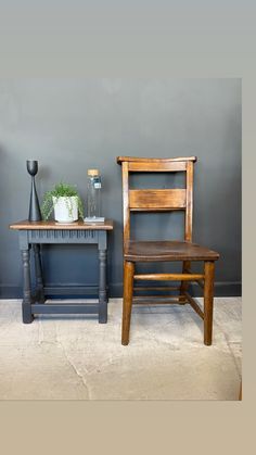 two wooden chairs sitting next to each other in front of a table with a vase on it