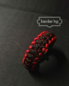 a red and black braided ring sitting on top of a black cloth covered floor